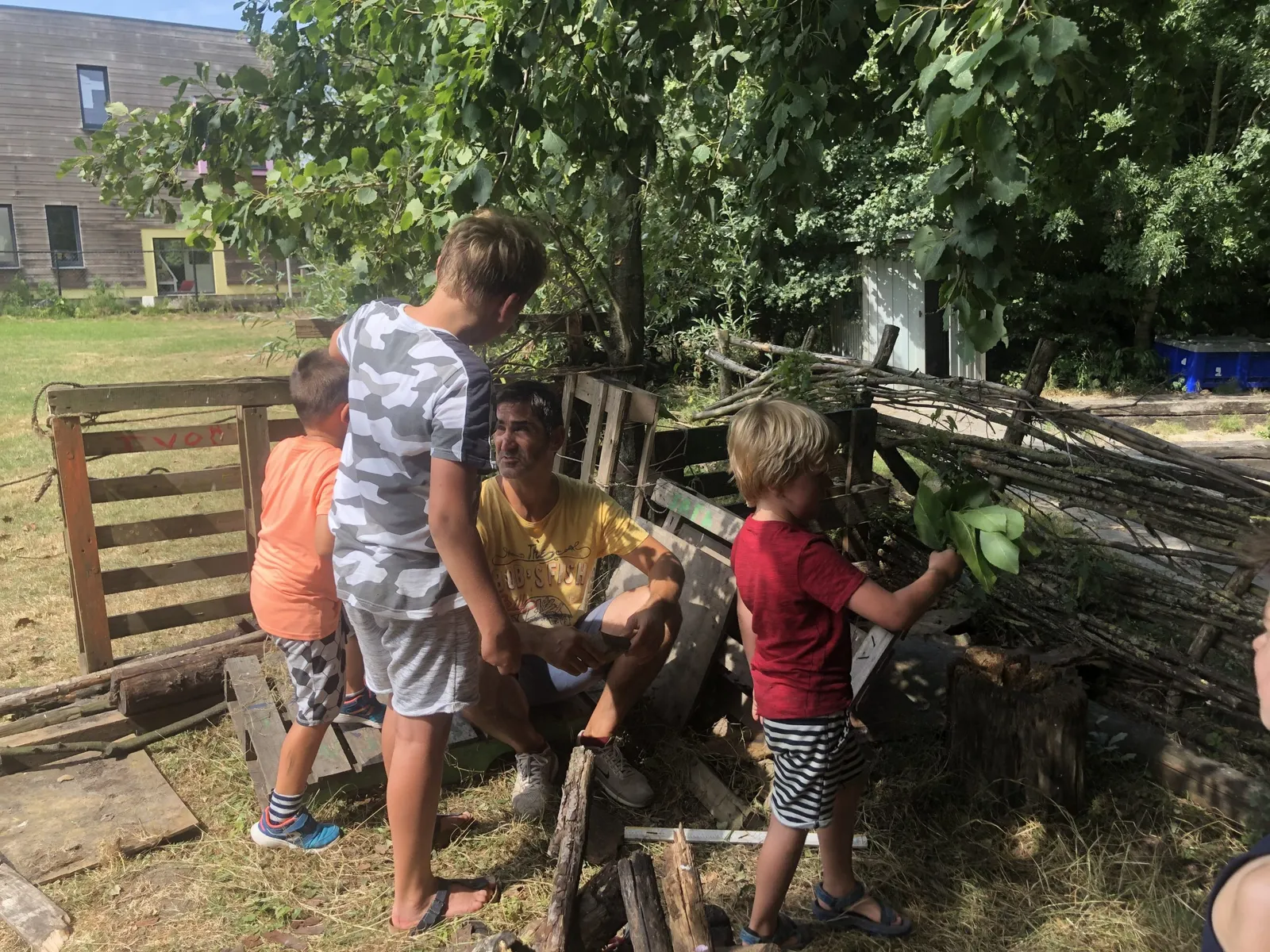 Kinderen bouwen samen een hut van pallets